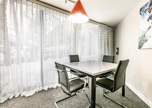 Enjoy meals in this stylish dining area with a large window, comfortable seating for four, and a beautiful piece of art on the wall.