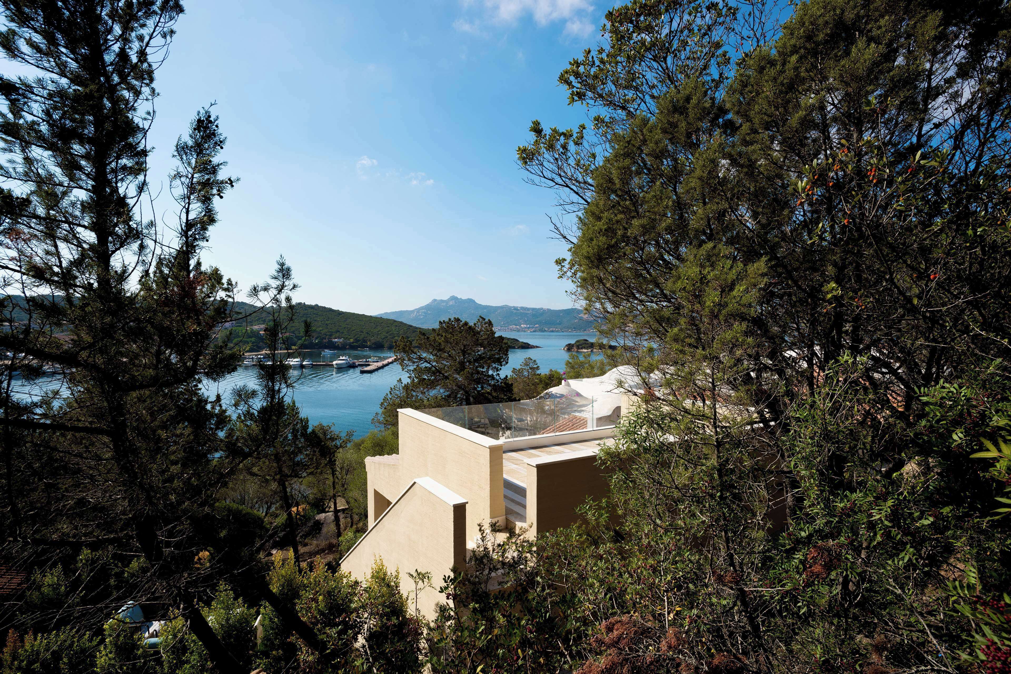 Un edificio moderno con techo de vidrio que ofrece vistas a una zona costera con montañas y una extensión de agua.