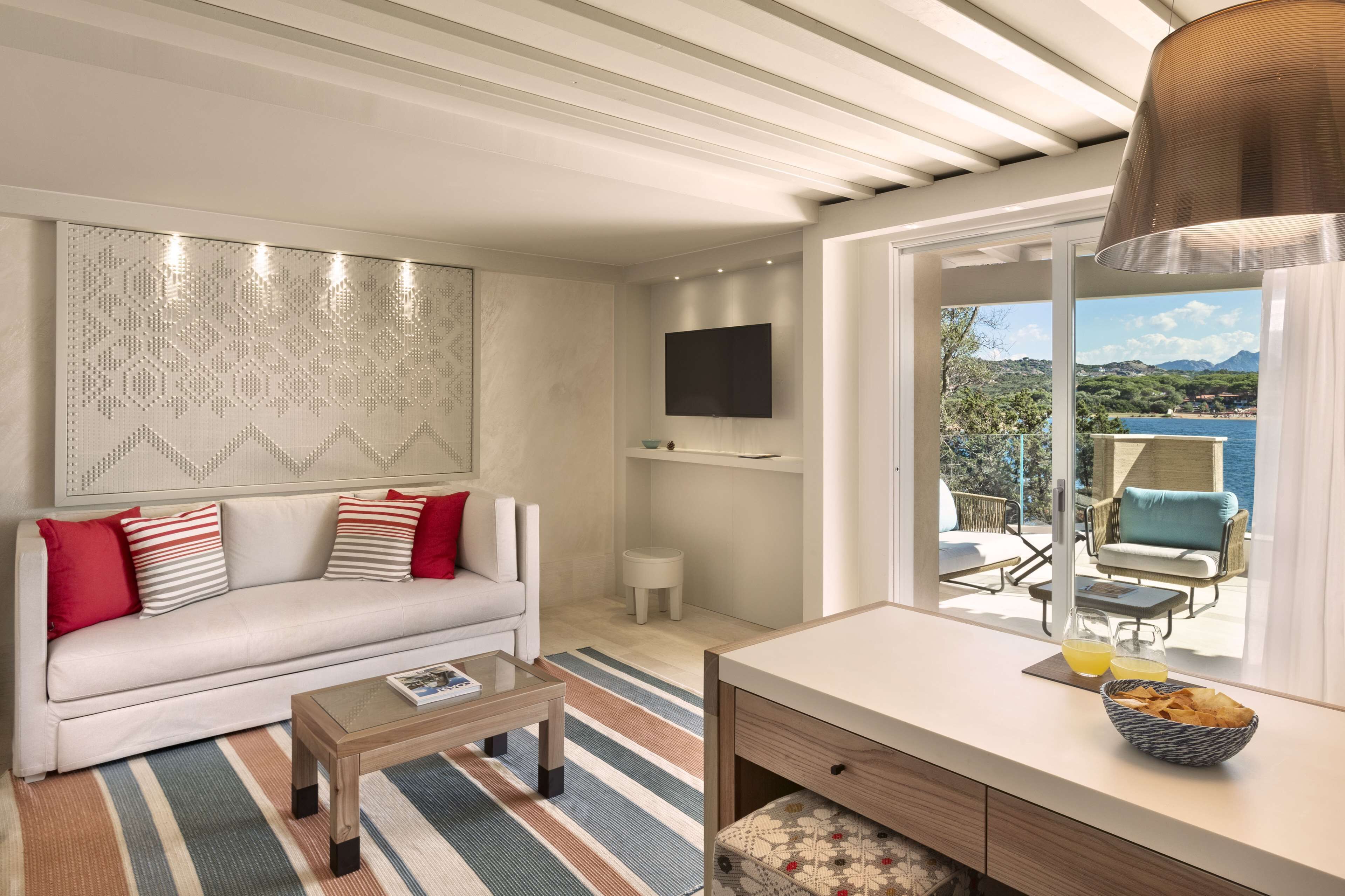 Un salon moderne avec un canapé, une table basse et une vue sur la mer grâce à de grandes fenêtres.