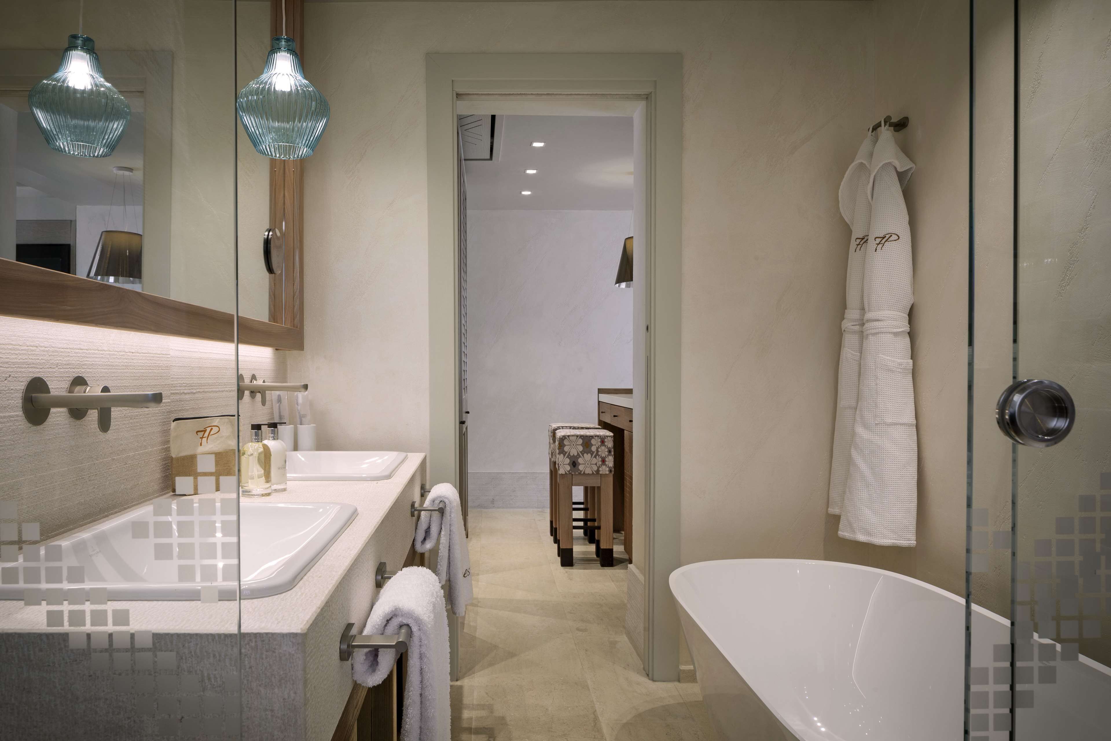A modern bathroom with two sinks, a glass-enclosed shower, and a visible door leading to another room.