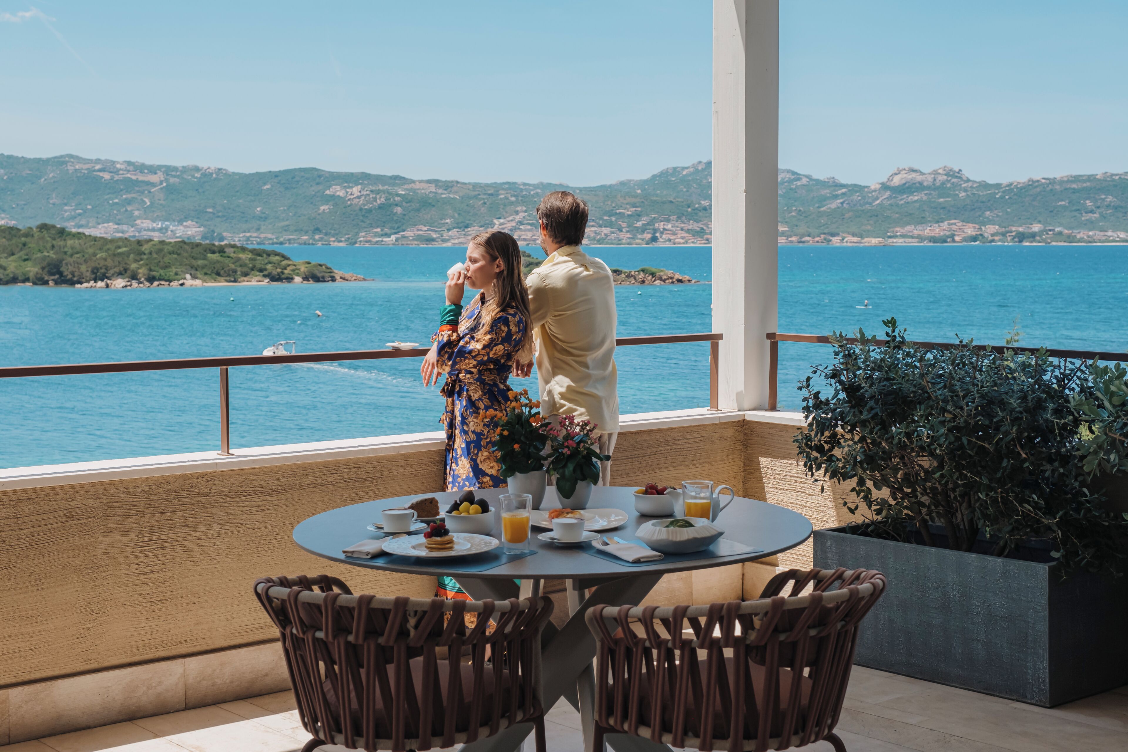 Een balkon met een ontbijttafel en uitzicht op de kust.