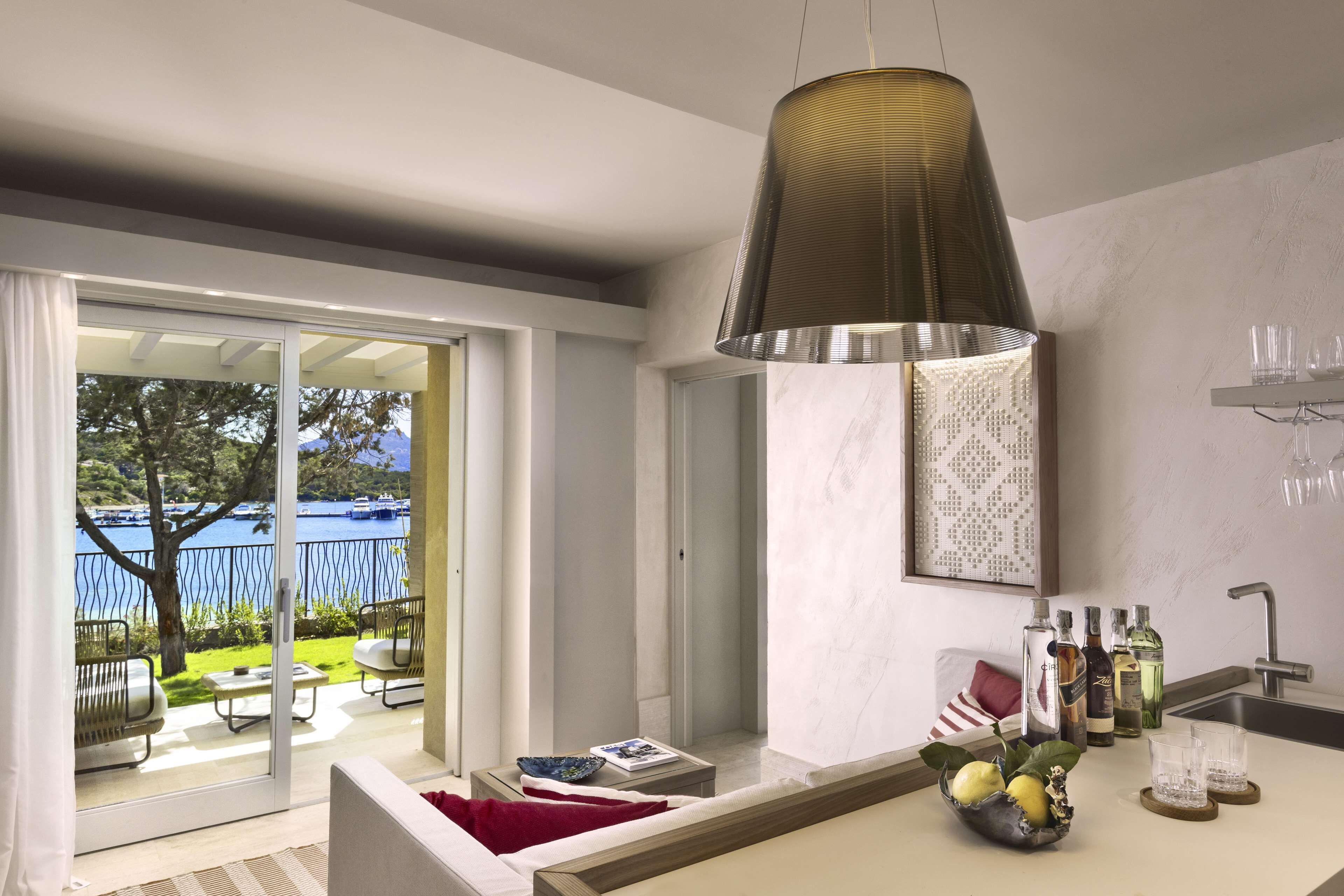 Una cucina moderna con un'ampia finestra, un lampadario a sospensione e un'area pranzo con un cuscino rosso.