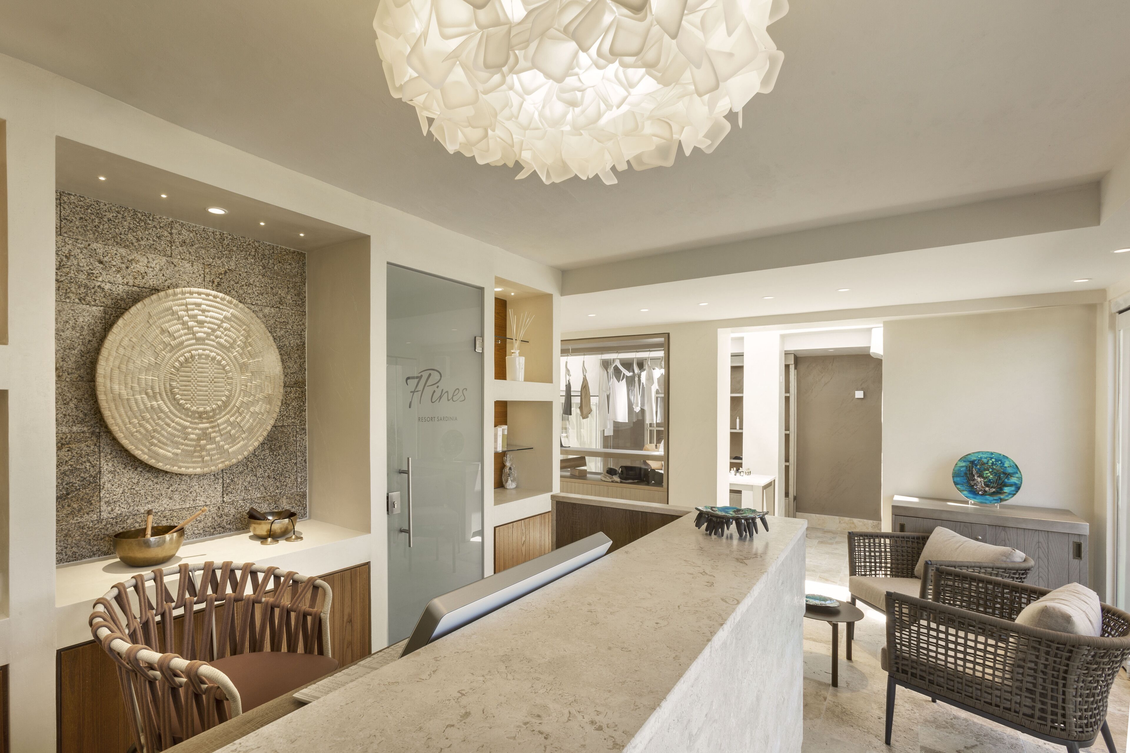 A modern kitchen with a central island, a dining area with wicker chairs, and a large decorative light fixture.