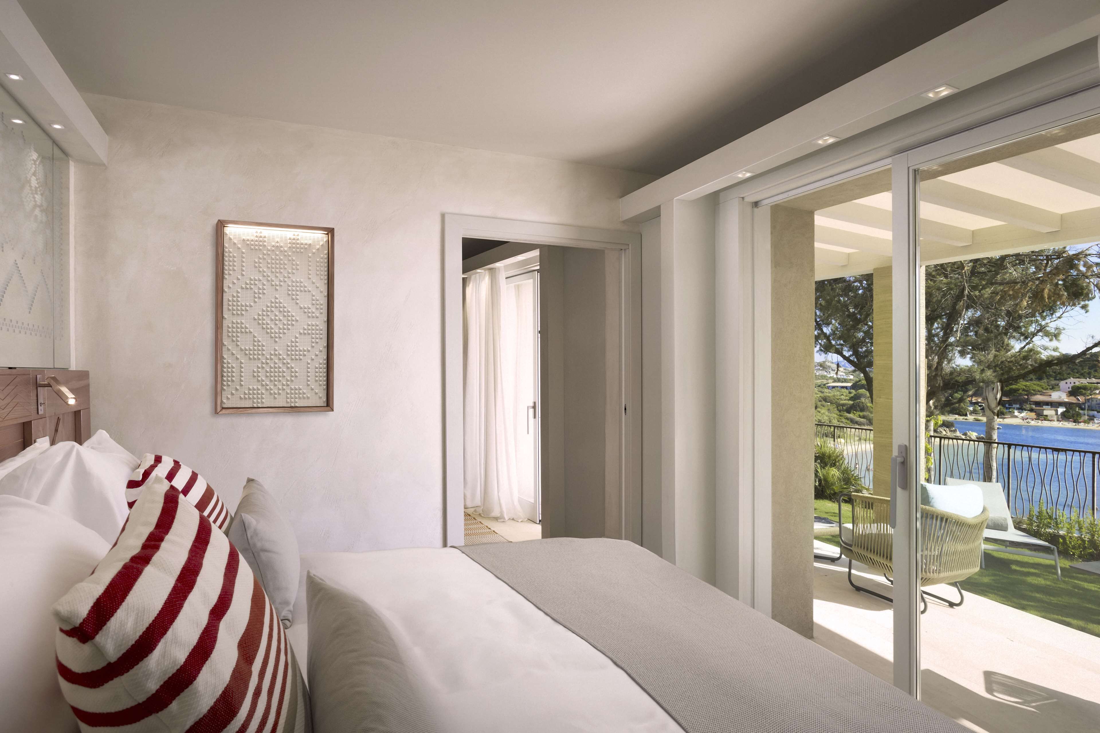 Une chambre à coucher moderne avec un grand lit, une vue sur le balcon et une œuvre d’art encadrée au mur.