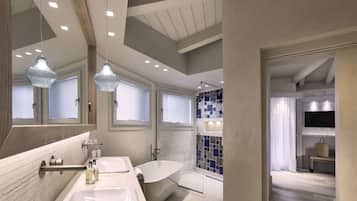 A modern bathroom with a freestanding bathtub, a large mirror, and pendant lighting.
