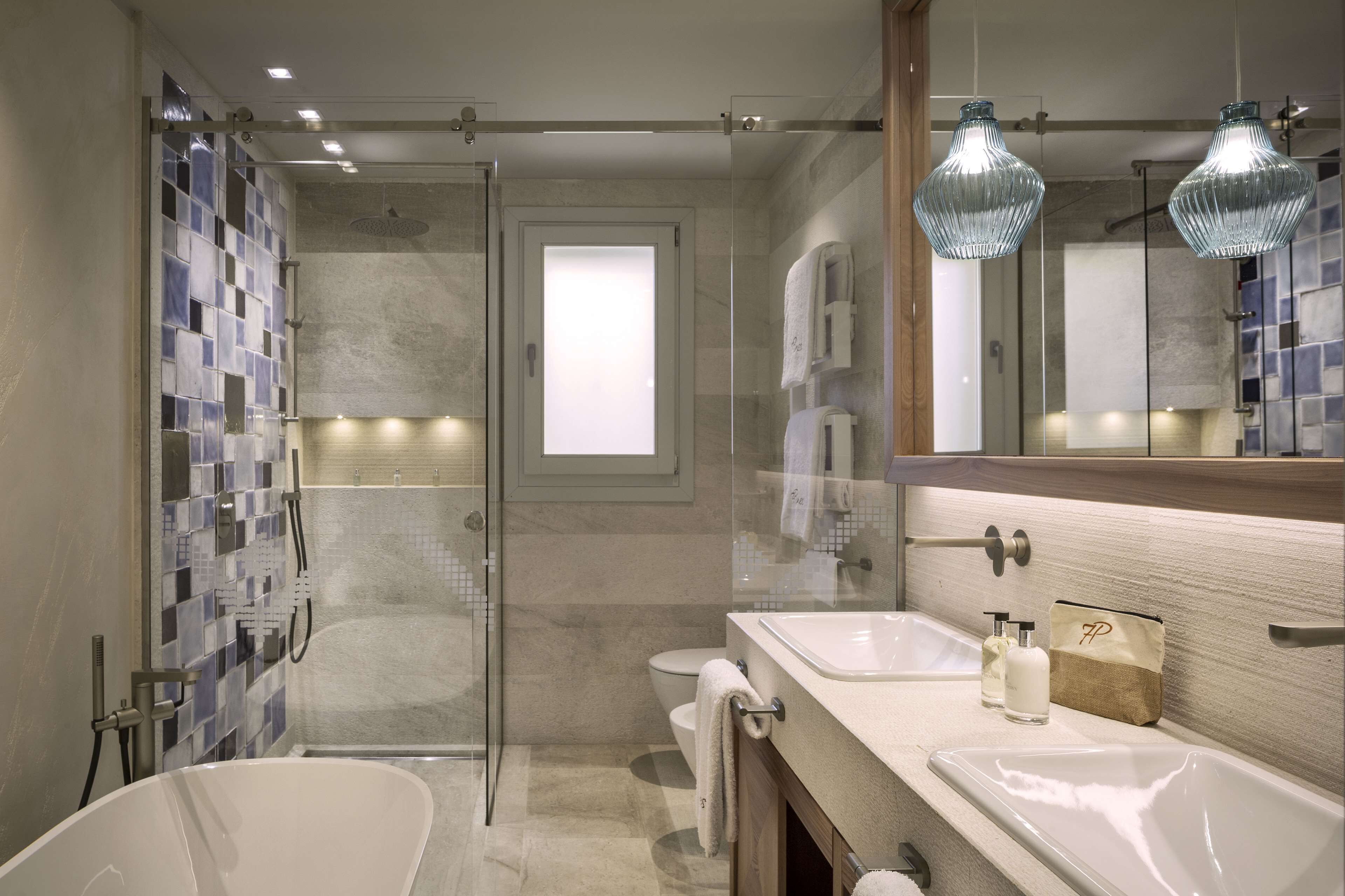 A modern bathroom with a glass shower enclosure, two sinks, and a large mirror.