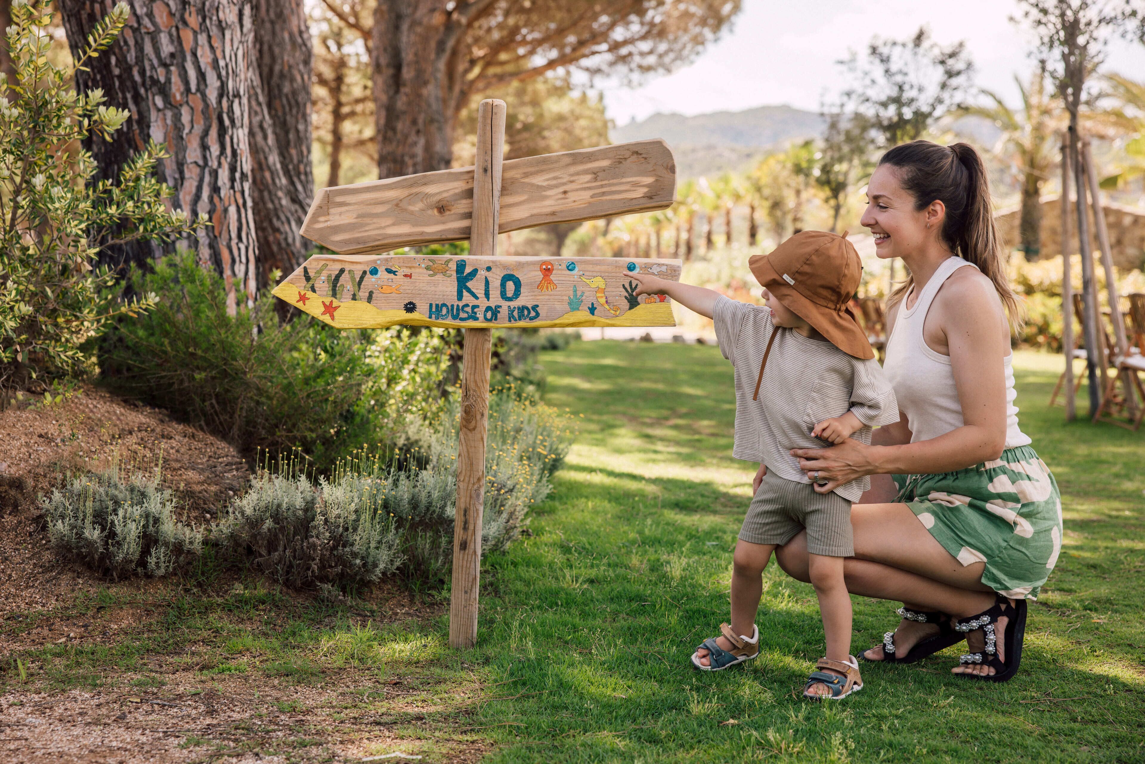 A wooden signpost with a child and an adult in a natural setting.