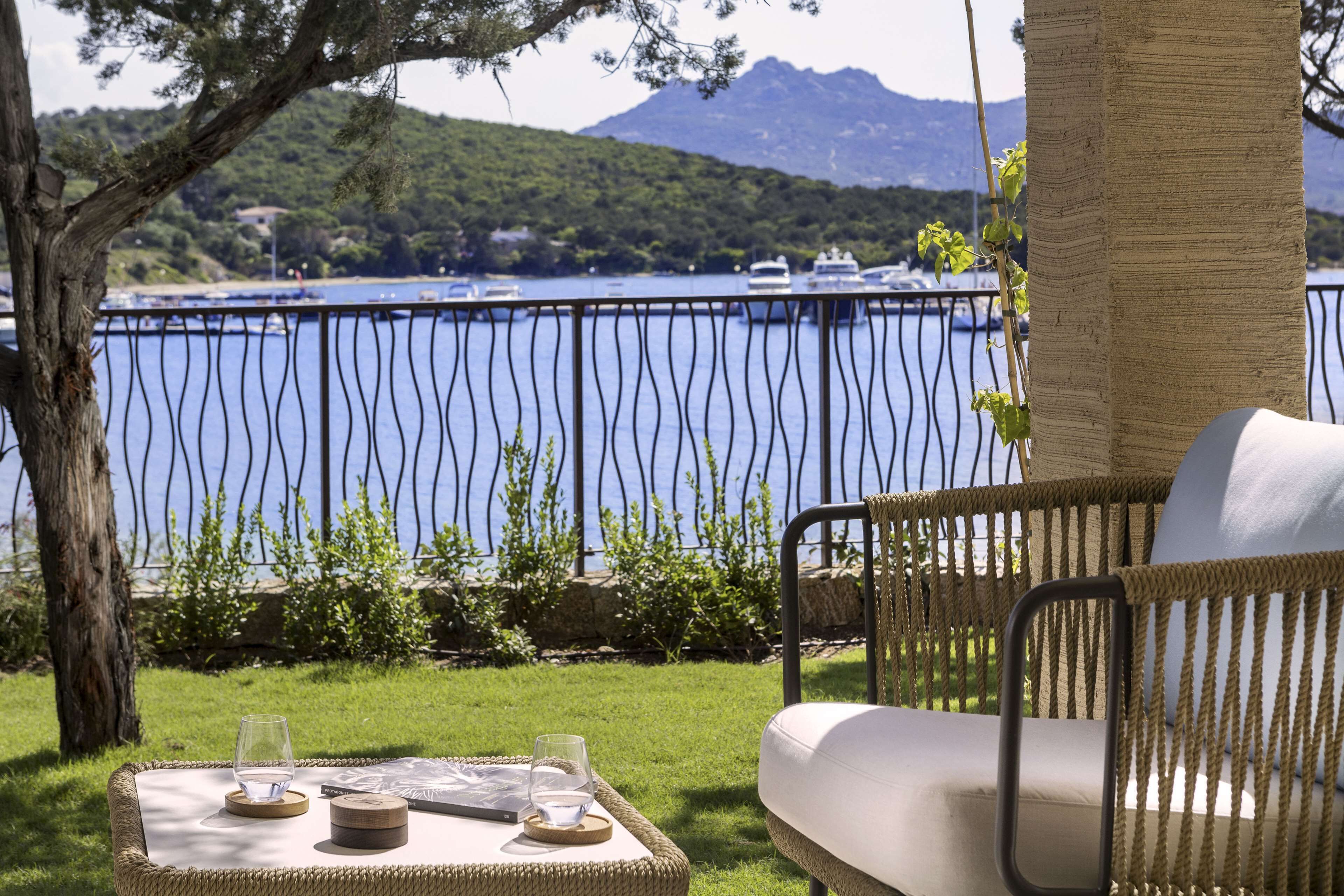 A wicker outdoor seating area with a view of a body of water and boats.