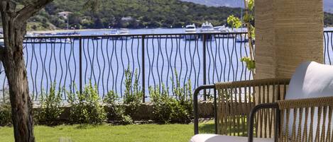 A wicker outdoor seating area with a view of a body of water and boats.