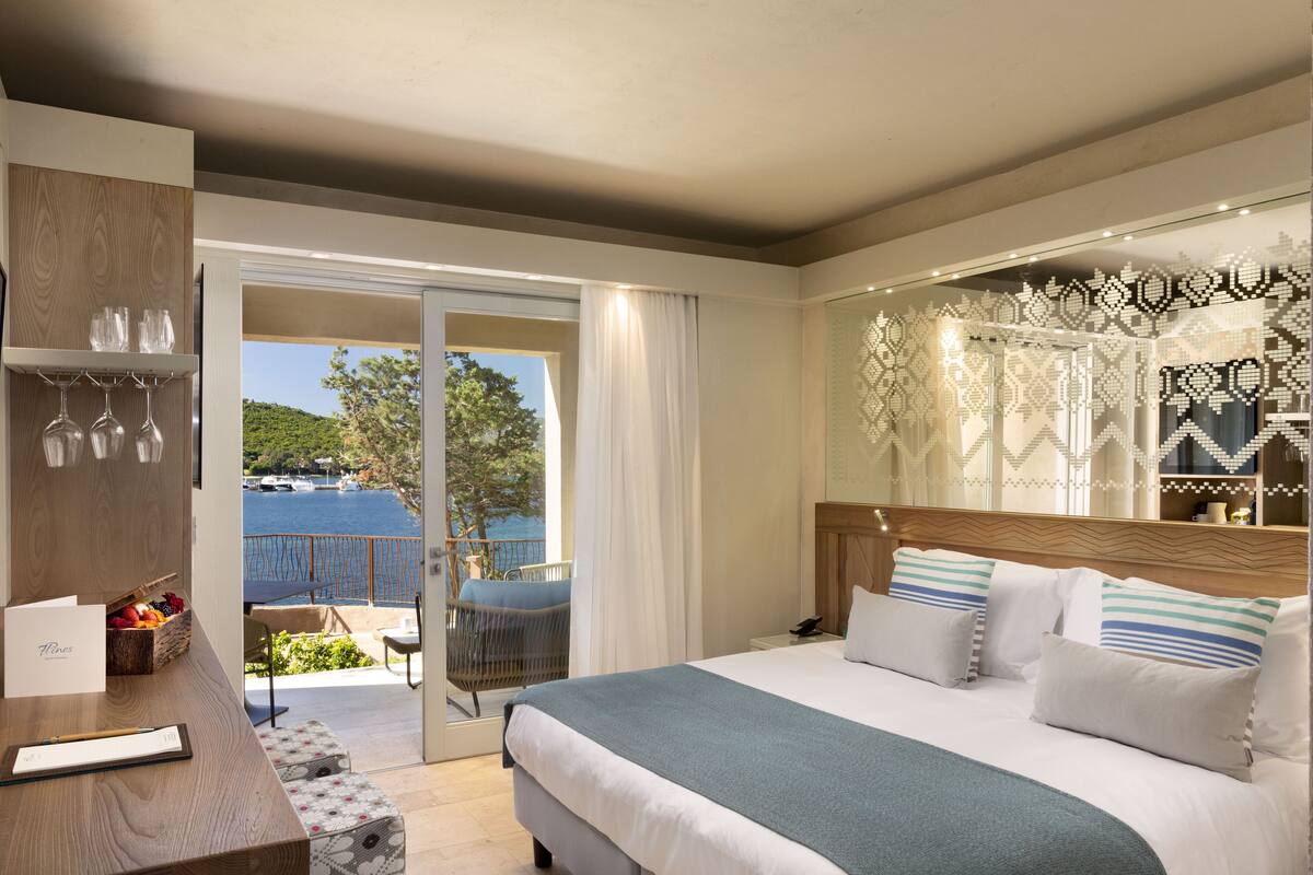 Une chambre d’hôtel avec un lit, une table de chevet et vue sur la mer.