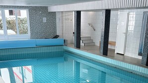 Une piscine intérieure dont les murs et le sol sont recouverts de carreaux.