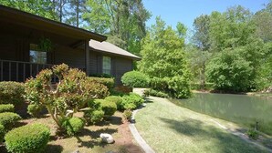 Une maison avec une pelouse bien entretenue, un étang et divers arbustes et arbres.