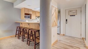 A modern kitchen with wooden cabinets, a microwave, and a bar area with stools. - Silver King 314 | 150 Yards to Lifts | Fireplace | Kitchen | Mountain View | Pool & Hot Tub (Park City)