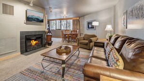 A living room with a fireplace, a sofa, a coffee table, and a dining area with a table and chairs. - Silver King 314 | 150 Yards to Lifts | Fireplace | Kitchen | Mountain View | Pool & Hot Tub (Park City)
