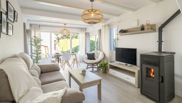 Una sala de estar moderna con un sofá, una mesa de centro, un televisor y una estufa de leña.