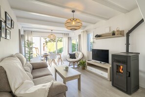 A modern living room with a sofa, a coffee table, a TV, and a wood-burning stove.