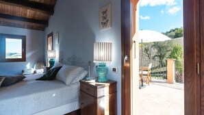 Ein Schlafzimmer mit Bett, Nachttischen, einer Lampe und einem Fenster mit Blick ins Freie.