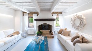 Amplia sala de estar con chimenea, sofás blancos y una mesa de centro azul.