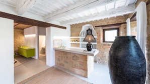 A modern kitchen with a stone wall, a green cabinet, a black vase, and a window.