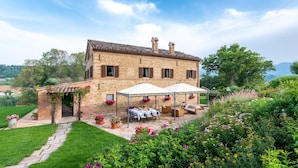 A stone house with a patio, outdoor seating, and flower beds.