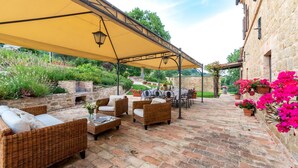 Un patio exterior con mobiliario de mimbre, una mesa y un toldo amarillo.