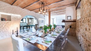 A dining area with a long table set for a meal, stone walls, and a wooden ceiling.