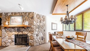 A dining area with a stone fireplace, wooden dining table, and chairs.