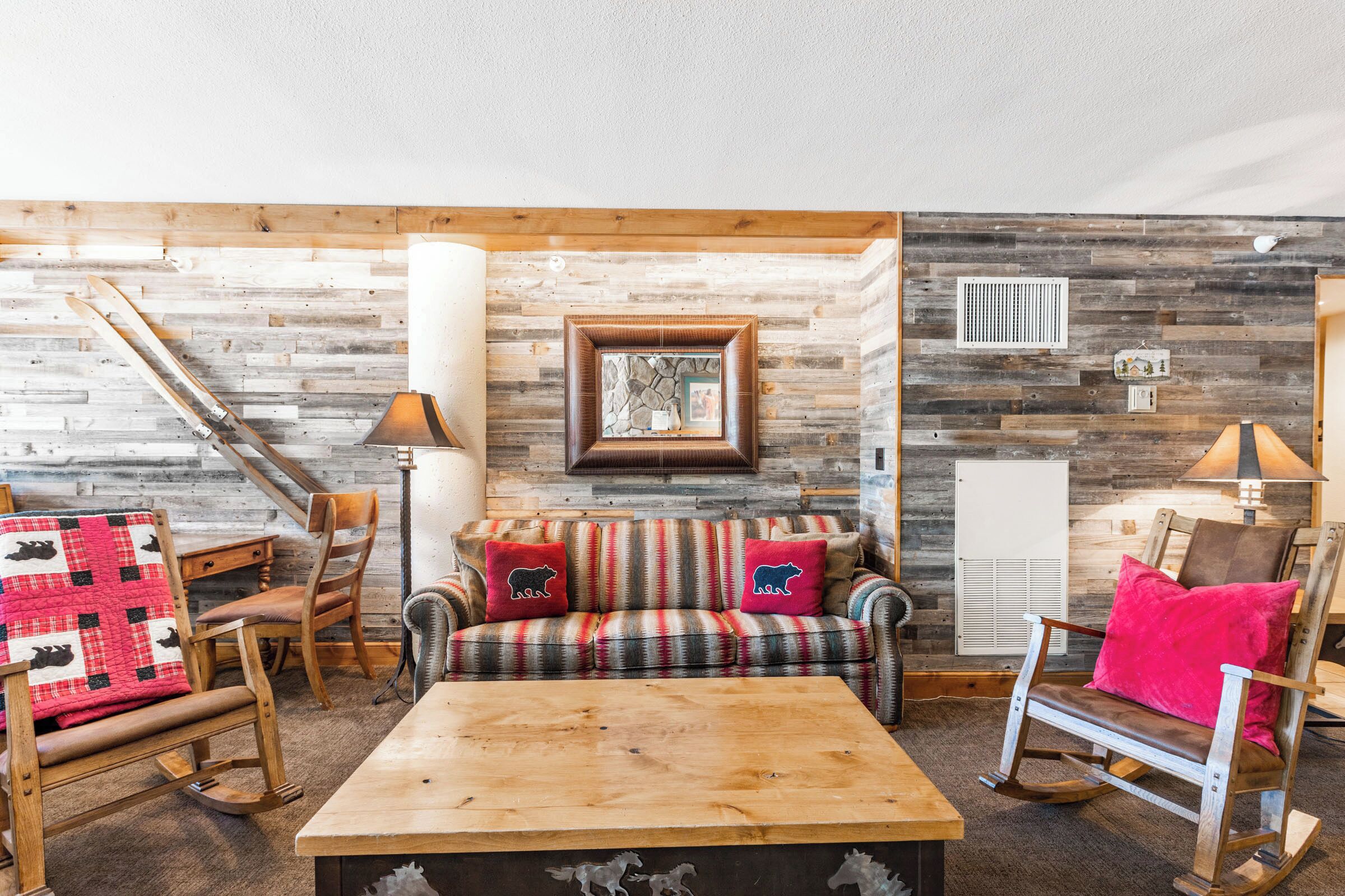 Una habitación acogedora con sofá escocés, sillón mecedora, mesa de centro de madera y chimenea.