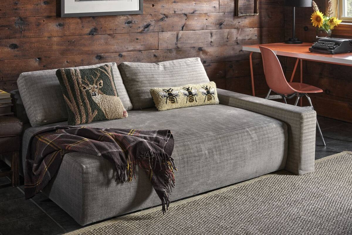 Ein gemütliches Zimmer mit Holzwand, einem gerahmten Bild, einem Schreibtisch mit Lampe und einem bequemen Sofa.