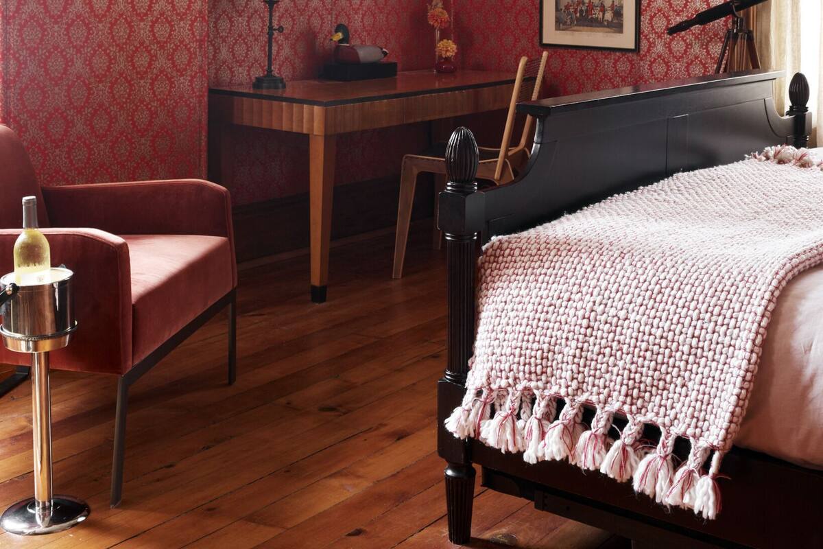 Ein Zimmer mit einem Bett, einem Schreibtisch, einem Sessel, einem Fernseher und einem Klavier.