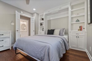 A bedroom with a bed, built-in shelving, a vanity with a mirror, and a door leading to a bathroom. - Casa Sul Lago by SoCharm | Lakefront Retreat |Pool| Dock (Troutman)