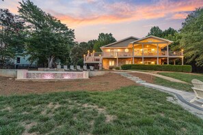 A two-story house with a covered porch, a stone retaining wall, and a well-maintained lawn.