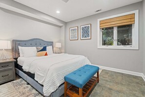 A bedroom with a bed, bedside tables, a bench, and two wall-mounted picture frames.