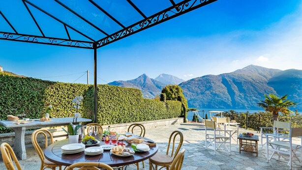 Un espace extérieur aménagé pour prendre les repas, offrant une vue sur les montagnes et un lac.