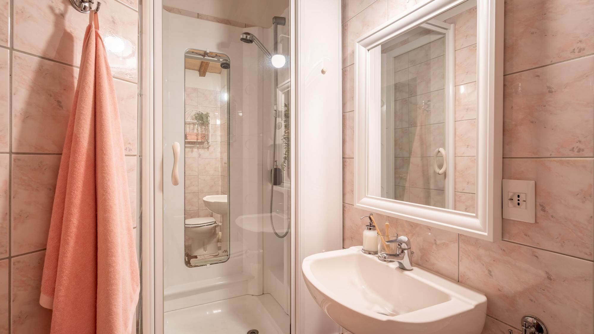 A bathroom with a glass-enclosed shower, a sink, and a mirror.
