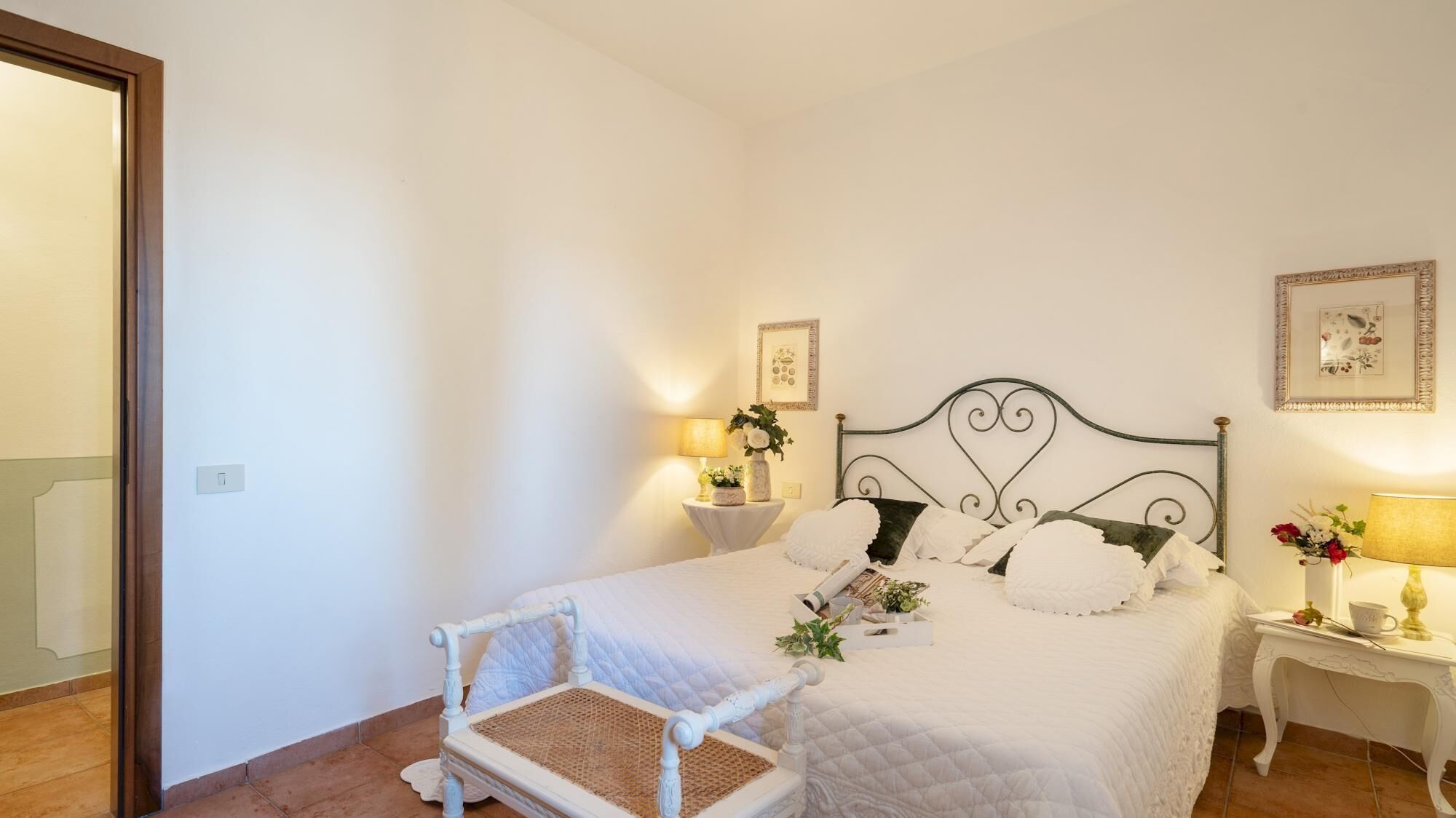 A neatly arranged bedroom with a bed, bedside tables, a chair, and a wall-mounted picture.