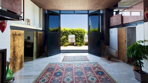 Une porte ouverte donne sur un jardin, et un tapis à motifs recouvre le sol.