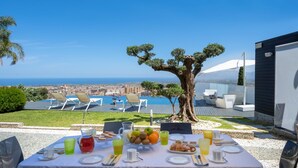 Une table à manger dressée avec des aliments pour le petit-déjeuner, offrant une vue sur la mer.