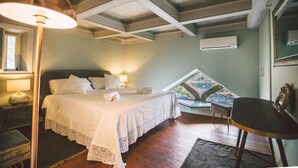 A bedroom with a bed, bedside lamps, a chair, a table, and a view through a window. - Torre Pirandello 6 in Taormina (Taormina)