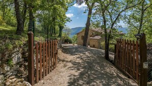 A gravel path leading to a stone building with a tiled roof, surrounded by trees and a stone wall. - Casa Largnano 6 2 in Arezzo (Castiglion Fiorentino)