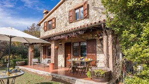 Una casa de piedra con un patio, mobiliario de exterior y un jardín.