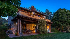 A rustic two-story house with a stone facade, a balcony, and a patio with outdoor furniture. - Villa Mila 6 in Gualdo Cattaneo (Gualdo Cattaneo)
