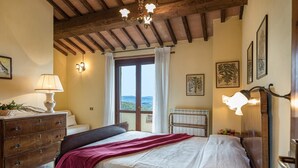 A bedroom with a bed, a dresser, a radiator, and a view of the outdoors. - Villa Mila 6 in Gualdo Cattaneo (Gualdo Cattaneo)