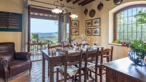 A dining area with a view of the landscape, wooden furniture, and framed artwork on the walls. - Villa Mila 6 in Gualdo Cattaneo (Gualdo Cattaneo)