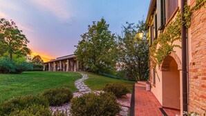 A building with a covered patio, a brick wall, and a stone pathway. - La Tana del Ghiro 20 (Roncofreddo)
