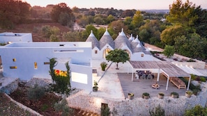 Une villa moderne avec des toits en pierre, un patio doté d’un espace salon extérieur et une vue sur le paysage environnant.