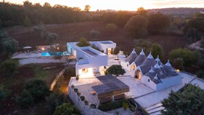 Eine moderne Villa mit Pool, mehreren Gebäuden und einer schönen Aussicht auf eine Hügellandschaft.