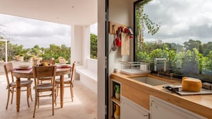 Eine moderne Küche mit großem Fenster und Blick auf einen Garten, Holzmöbel und einer eingebauten Spüle.
