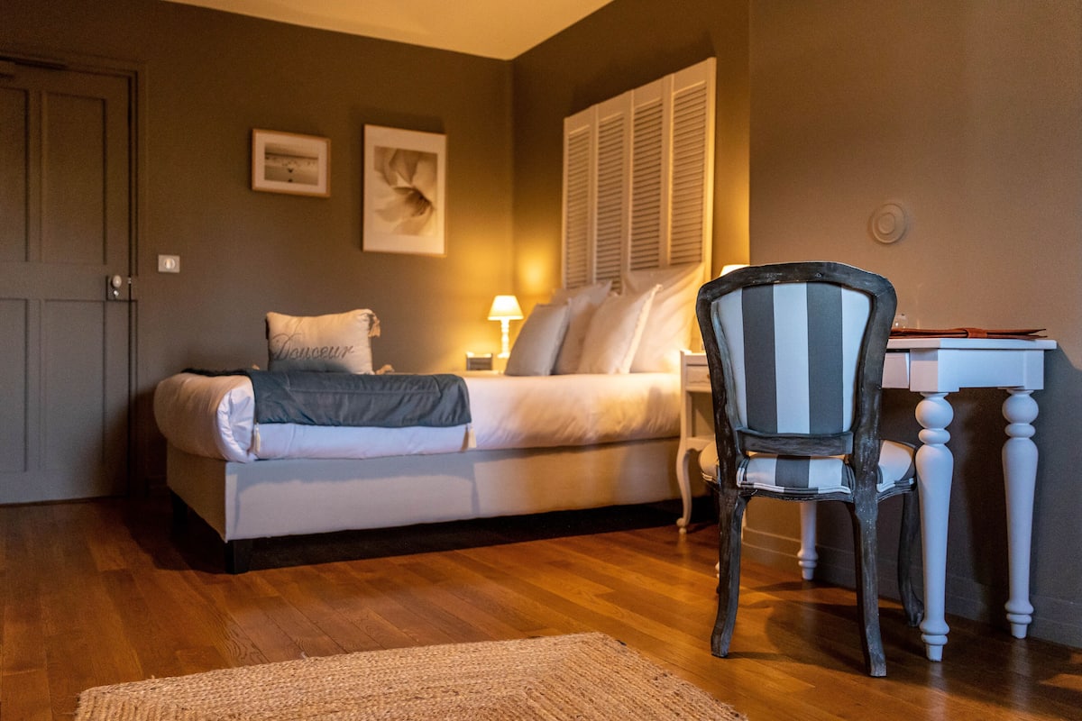 Un dormitorio con cama, una silla, un escritorio y una lámpara.
