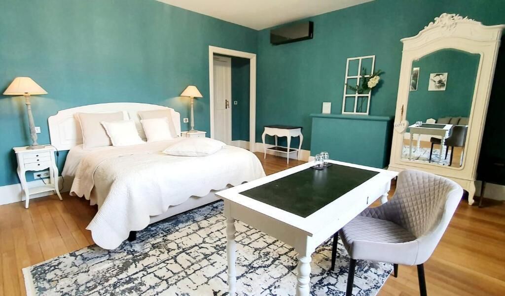 A bedroom with a bed, bedside tables, a desk, a chair, a mirror, and a rug.